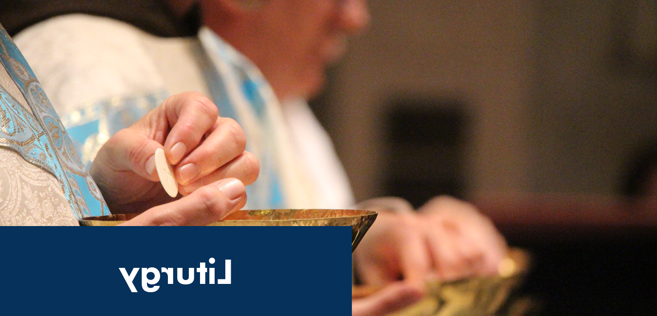 Image of a priest's hands serving a communion host at liturgy or mass