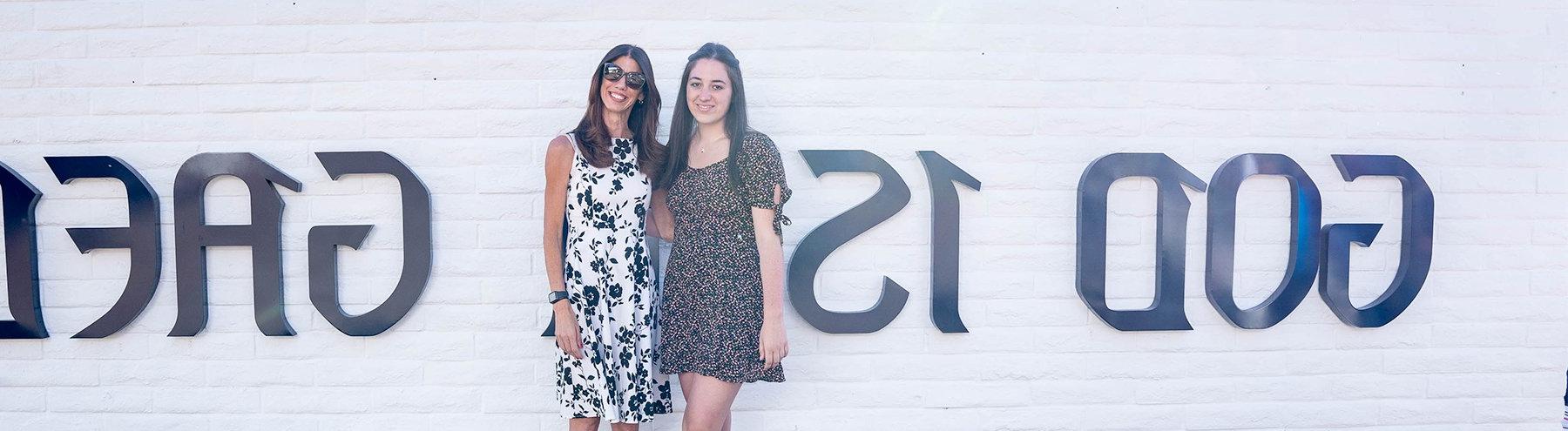 Two people pose in front of a SMC sign that says God is a Gael