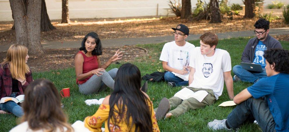 A professor teaching a Shakespeare class outside on the grass