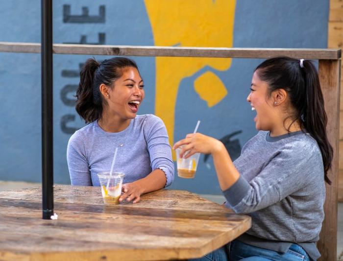 Two friends laugh over drinks