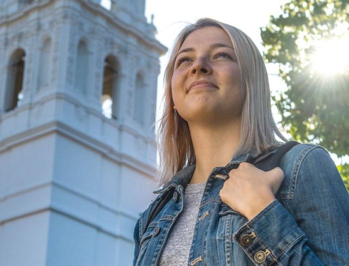 business student in front of chapel smiling